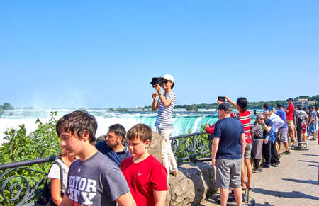 NIAGARA FALLS, CANADA - JULY 25, 2019: People taking selfie over Niagara Falls on a beautiful clear sunny day. Canadian view. Niagara Falls are three waterfalls at the southern end of Niagara Gorgeのeditorial素材