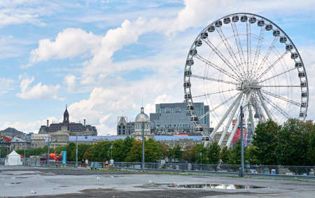 Canada, Montreal - July 11, 2021: Scenic view of ferris wheel La Grande Roue de Montreal in Old Port of Montreal over blue skies and clouds. The Old Port of Montreal is the historic port in Quebec.のeditorial素材