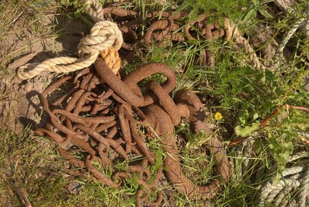old rusty fishermans chain, rope and links lying in grassの写真素材