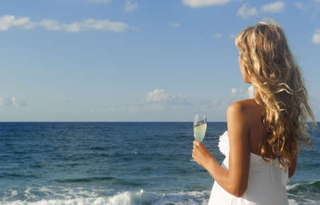 Beautiful woman in white dress looking at the seaの写真素材
