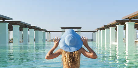 Beautiful blonde woman relaxing near extraordinary pool in sunny dayの写真素材