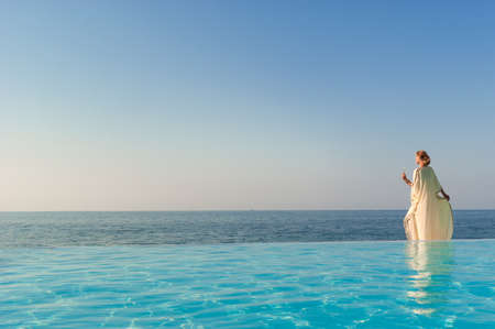 View of antique greek woman near infinity pool on a coastの写真素材
