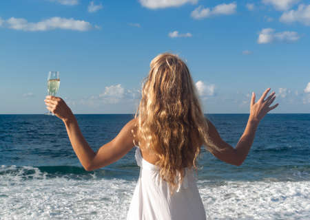 Happy woman in white dress near sea looking farの写真素材