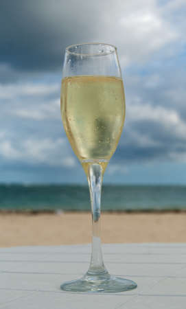 Glass of white wine on caribbean beach at sunsetの写真素材