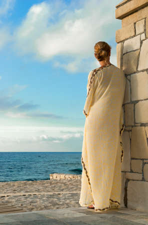 Greek style woman in long silk dress looking for the seaの写真素材