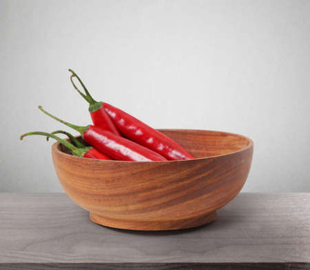Red Hot Chili Peppers in bowl over woodenの写真素材