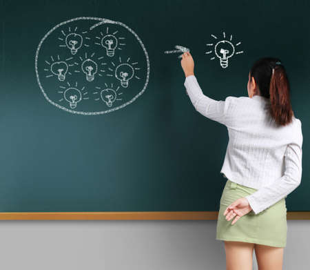 Thought drawing light bulb with chalk on black chalkboardの写真素材