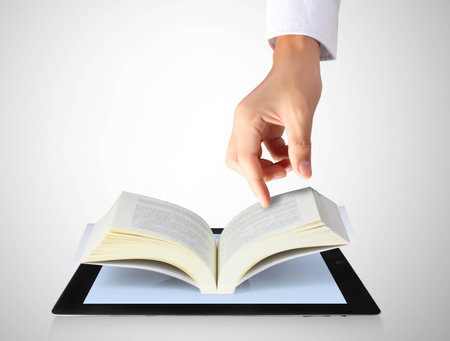 holding touch screen tablet and shows tablet in hand and open the bookの写真素材