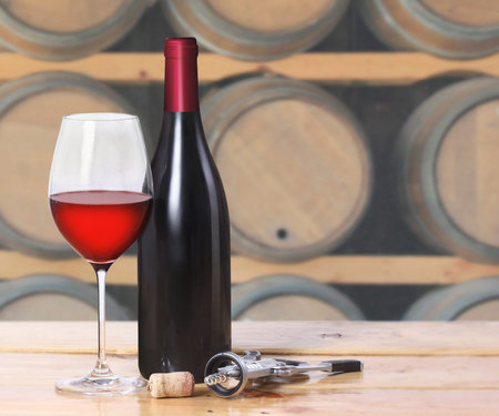 Red wine bottle, one glass on old wooden 