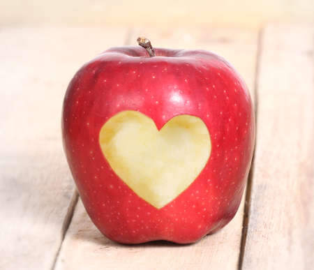 apple with heart shape Isolated on wood background の写真素材