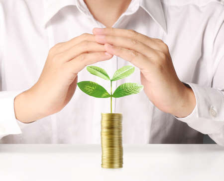 Businessman holding plant sprouting from a handful of coinsの写真素材