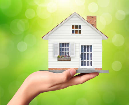 holding house representing home ownership and the Real Estate businessの写真素材
