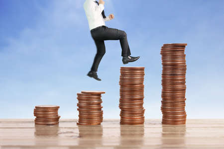 Businessman walk on stack of coins which grows success and investmentの写真素材