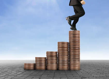 Businessman walk on stack of coins which grows success and investmentの写真素材