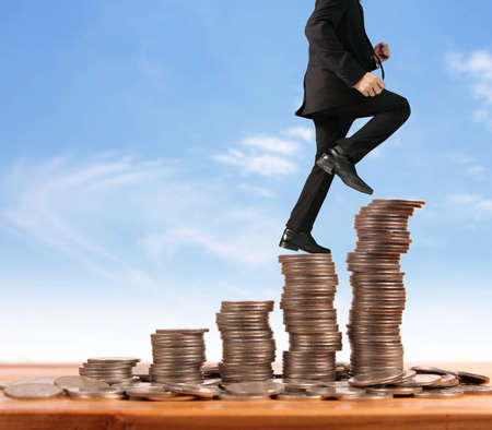 Businessman walk on stack of coins which grows success and investmentの写真素材