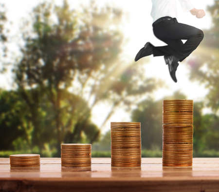 Businessman walk on stack of coins which grows success and investmentの写真素材