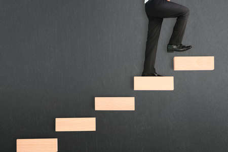 business person stepping up a toy staircaseの写真素材