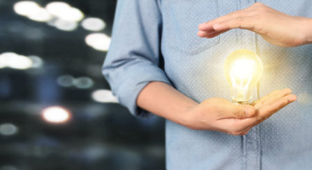 Hand holding illuminated light bulb, idea, innovation and inspiration concept