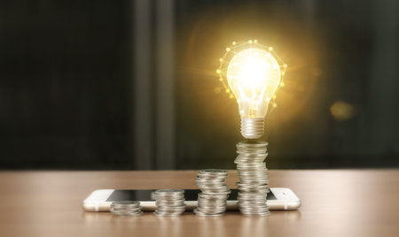 light bulb on top of coins and a smartphone