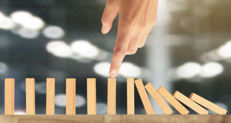 Hand stopping the Domino effect stopped by uniqueの写真素材