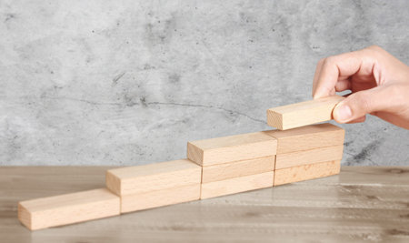 Hand liken person stepping up wood block stacking as step stair, business idea