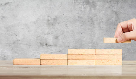 Hand liken person stepping up wood block stacking as step stair, business idea