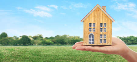 Mortgage concept by money house. holding a house model in handの写真素材