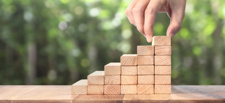 Hand liken person stepping up a toy staircase wood