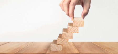 Hand liken person stepping up a toy staircase woodの写真素材