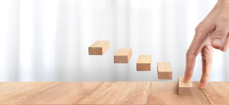 Hand liken person stepping up a toy staircase woodの写真素材