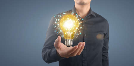 Hand of holding illuminated light bulb, idea, innovation inspiration conceptの写真素材