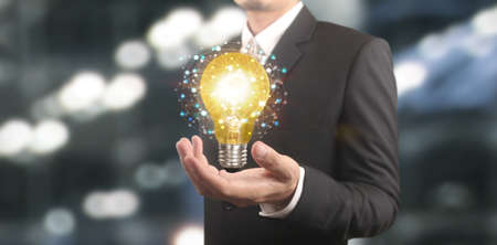 Hand of holding illuminated light bulb, idea, innovation inspiration conceptの写真素材