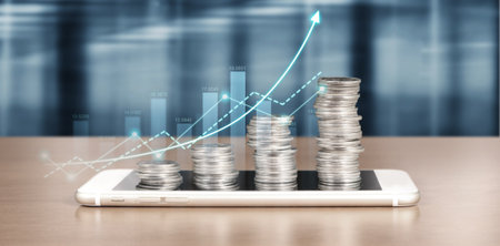 smartphone screen next to growing piles of coins and chart positive indicators in his businessの写真素材