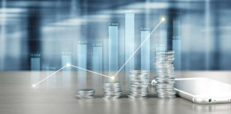 smartphone screen next to growing piles of coins and chart positive indicators in his businessの写真素材