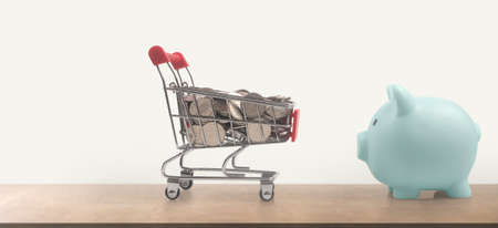 Toy shopping cart with coins and Piggy bank. Consumer society trendの写真素材