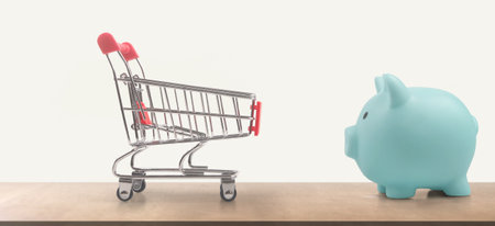 Toy shopping cart and Piggy bank. Consumer society trendの写真素材