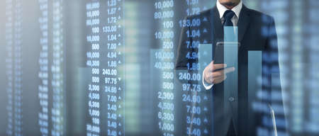Hand holding smartphone device and touching screen. Stock exchange market concept. businessman trader looking on with graphs analysis candleの写真素材