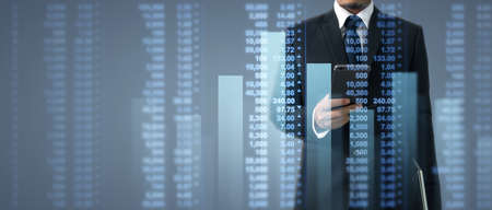 Hand holding smartphone device and touching screen. Stock exchange market concept. businessman trader looking on with graphs analysis candleの写真素材