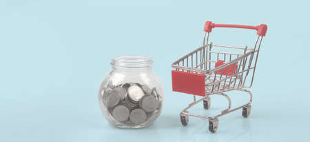 Toy shopping cart with coins and Piggy bank. Consumer society trendの写真素材