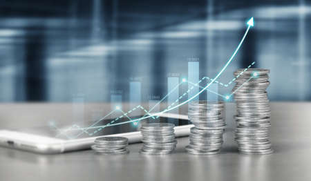 smartphone screen next to growing piles of coins and chart positive indicators in his businessの写真素材