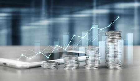 smartphone screen next to growing piles of coins and chart positive indicators in his businessの写真素材
