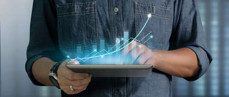 Businessman plan graph growth and increase of chart positive indicators in his business on tablet in handの写真素材