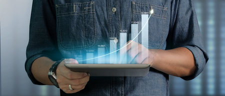 Businessman plan graph growth and increase of chart positive indicators in his business on tablet in handの写真素材