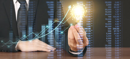 Hand of holding illuminated light bulb and increase of chart positive indicators in his businessの写真素材