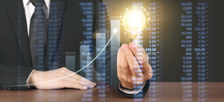 Hand of holding illuminated light bulb and increase of chart positive indicators in his businessの写真素材