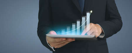 Businessman plan graph growth and increase of chart positive indicators in his business,tablet in handの写真素材