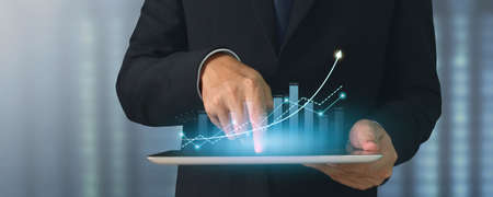 Businessman plan graph growth and increase of chart positive indicators in his business,tablet in handの写真素材