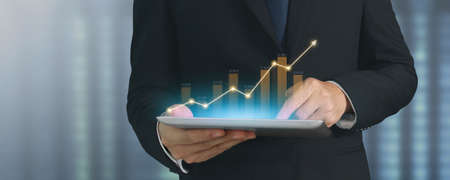 Businessman plan graph growth and increase of chart positive indicators in his business,tablet in handの写真素材