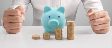 Man hand put coin money to piggy bank, saving and deposit money conceptの写真素材