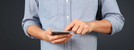 Man holding smartphone in hand device and touching screenの写真素材